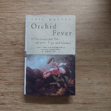 Book titled 'Orchid Fever' by Eric Hansen on a wooden surface