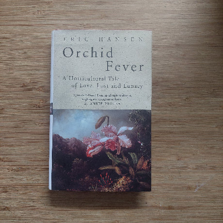 Book titled 'Orchid Fever' by Eric Hansen on a wooden surface