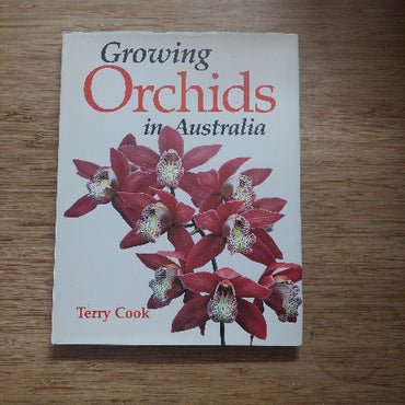 Book titled 'Growing Orchids in Australia' by Terry Cook on a wooden surface