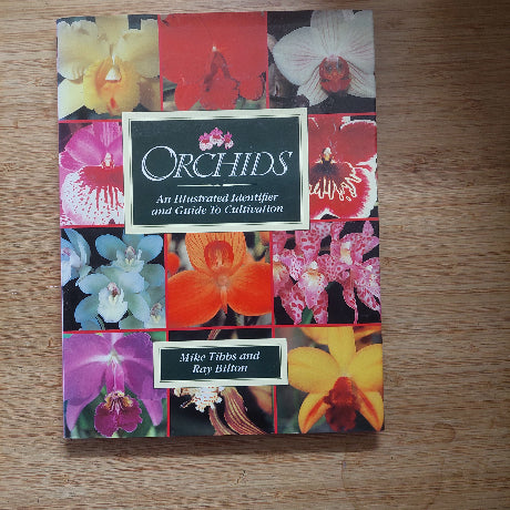 Book cover with colorful orchid images on a wooden surface