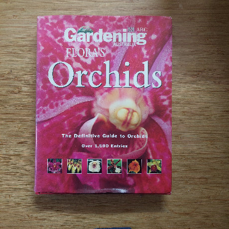 Book titled 'Flora's Orchids' on a wooden surface
