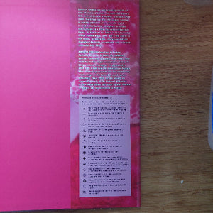Pink paper with printed text on a wooden surface